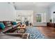 Open living room features a leather sofa, blue rug, hardwood floors, and a view into the kitchen at 8612 Summerville Pl, Orlando, FL 32819