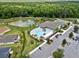 Aerial view of community pool, pond and amenities surrounded by lush greenery and trees at 6231 Atkinson Ln, The Villages, FL 32163