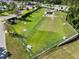 Aerial view of a spacious fenced dog park with a covered shelter and seating areas at 6231 Atkinson Ln, The Villages, FL 32163