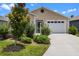 Inviting home with an attached garage, lush green bushes, and a well-manicured lawn at 6231 Atkinson Ln, The Villages, FL 32163
