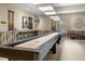 Inviting game room with a shuffleboard table, bar seating, and stylish wall décor at 6231 Atkinson Ln, The Villages, FL 32163