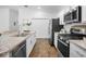 Modern kitchen featuring stainless steel appliances, granite countertops, and hardwood flooring at 6231 Atkinson Ln, The Villages, FL 32163