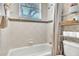 Cozy bathroom with tiled walls, bathtub with shower, and a decorative shelf at 1017 Parkside Pointe Blvd, Apopka, FL 32712