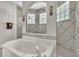 Bright bathroom showcasing a large soaking tub, tiled shower, decorative wall accents, and natural light at 1017 Parkside Pointe Blvd, Apopka, FL 32712