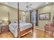 Primary bedroom features a four-poster bed, hardwood flooring, stylish window treatments, and elegant furnishings at 1017 Parkside Pointe Blvd, Apopka, FL 32712