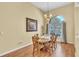 A charming dining area with hardwood floors, a round wood table and chairs, chandelier, and a large arched window at 1017 Parkside Pointe Blvd, Apopka, FL 32712