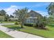 Charming home exterior featuring a lush green lawn, mature trees, and sidewalk access at 1017 Parkside Pointe Blvd, Apopka, FL 32712