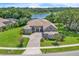 Beautiful home exterior with a paver driveway, lush landscaping, and a scenic lake view in the background at 1017 Parkside Pointe Blvd, Apopka, FL 32712
