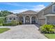 Inviting home with an arched entryway, stone accents, manicured landscaping, and a patterned brick driveway at 1017 Parkside Pointe Blvd, Apopka, FL 32712
