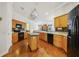 Well-equipped kitchen with hardwood floors, wooden cabinets, black appliances, and a center island at 1515 Cherry Lake Way, Lake Mary, FL 32746
