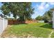 Spacious backyard with a brick fence, green lawn, and mature trees offering privacy at 15411 Taurus Ct, Mascotte, FL 34753