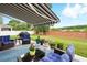 Charming patio with awning, outdoor seating, blue rug, and a lush backyard view at 15411 Taurus Ct, Mascotte, FL 34753