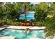 Couple relaxing in hot tub with pool in the background and lush vegetation at 15695 Grove Resort Ave # 4412, Winter Garden, FL 34787