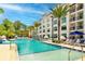 Resort-style pool with clear turquoise water, surrounded by palm trees, sun loungers and a modern building exterior at 15695 Grove Resort Ave # 4412, Winter Garden, FL 34787