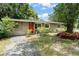 Quaint one-story home with mature trees, lush landscaping, and an inviting red front door at 17 S Aurora Dr, Apopka, FL 32703