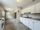 A kitchen featuring white cabinets and appliances, with an adjacent carpeted room, ideal for easy access at 221 Golden Days Dr, Casselberry, FL 32707
