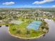 Aerial view of community with tennis and basketball courts beside a pond surrounded by mature trees and landscaped grounds at 2528 Double Tree Pl, Oviedo, FL 32766