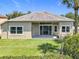 A well-manicured backyard featuring a lush lawn, mature landscaping, and a covered patio at 2528 Double Tree Pl, Oviedo, FL 32766