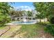Backyard view of a sparkling pool surrounded by a well-maintained lawn, home and mature trees at 2666 Derbyshire Rd, Maitland, FL 32751