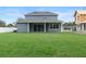 Large backyard with a gray home and a patio with sliding glass doors and an under construction house at 3022 Peel Ave, Orlando, FL 32806