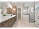 Bathroom showcases dual vanities, stone countertops, a glass-enclosed shower with tile surround, and storage at 3022 Peel Ave, Orlando, FL 32806