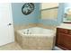 Corner soaking tub, vanity with a tan countertop, and neutral-toned tile at 319 Morning View Dr, Winter Garden, FL 34787