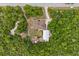 An aerial view shows a home with a long driveway, metal storage building, and lush green trees for privacy at 41128 Apple St, Eustis, FL 32736