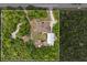 An aerial view shows a home with a long driveway, metal storage building, and lush green trees for privacy at 41128 Apple St, Eustis, FL 32736