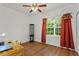 Bright bedroom featuring wood floors, window with red curtains, and a ceiling fan at 41128 Apple St, Eustis, FL 32736