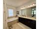 Bathroom featuring a soaking tub with tile surround, double vanity, and elegant fixtures at 541 Kistler Cir, Clermont, FL 34715