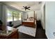 Primary bedroom with a wooden four-poster bed, dark floors, and a beautiful view out the window at 541 Kistler Cir, Clermont, FL 34715