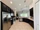 Modern kitchen features stainless steel appliances, dark wood cabinetry, and tile flooring that extends into the living area at 541 Kistler Cir, Clermont, FL 34715
