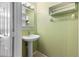 Cozy half bathroom with a pedestal sink, neutral green wall, and simple shelving for convenient storage at 6360 Ranelagh Dr # 104, Orlando, FL 32835