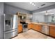 Well-lit kitchen featuring stainless steel appliances, wood cabinets, tiled backsplash, and view to adjacent room at 6360 Ranelagh Dr # 104, Orlando, FL 32835