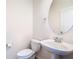 Cozy powder room featuring a pedestal sink, round mirror, and neutral color palette at 7508 Bentonshire Ave, Windermere, FL 34786