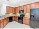 Spacious kitchen with wood cabinetry, granite countertops and backsplash, and black appliances at 7508 Bentonshire Ave, Windermere, FL 34786