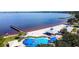 Aerial view of a lakefront beach and splash pad with beach with pier and shaded picnic areas at 13631 Via Roma Cir, Clermont, FL 34711