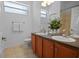 Well-lit bathroom featuring dual sinks, neutral tile floors, and wooden cabinets at 13631 Via Roma Cir, Clermont, FL 34711