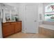 Bathroom featuring a stained-glass window above the bathtub, tiled floors and wooden cabinets at 13631 Via Roma Cir, Clermont, FL 34711