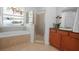 Bathroom featuring a stained-glass window above the bathtub, glass shower, and wooden cabinets at 13631 Via Roma Cir, Clermont, FL 34711