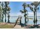 Picturesque pier leading to a gazebo on a tranquil lake, framed by Spanish moss-draped trees at 13631 Via Roma Cir, Clermont, FL 34711