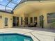 Covered patio area featuring a beautiful pool with crystal blue water, seating, and well-maintained landscaping at 13631 Via Roma Cir, Clermont, FL 34711