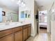 Bathroom featuring double sinks, wood cabinets, and a doorway leading to a bedroom at 1478 Moon Valley Dr, Davenport, FL 33896