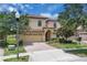 Charming two-story home with manicured lawn, mature trees, and brick-paved driveway at 1478 Moon Valley Dr, Davenport, FL 33896