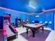 Spacious game room with arcade games, pool table, and sleek blue walls with colorful accents at 1478 Moon Valley Dr, Davenport, FL 33896