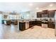Open-concept kitchen flows into the living area, showcasing stainless appliances, granite counters, and dark wood cabinets at 1478 Moon Valley Dr, Davenport, FL 33896