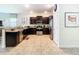 Bright, open kitchen featuring stainless steel appliances, granite counters, tile floors, and dark wood cabinetry at 1478 Moon Valley Dr, Davenport, FL 33896