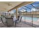 Covered patio with table and chairs next to a screened-in pool with safety fence at 1478 Moon Valley Dr, Davenport, FL 33896