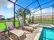 Comfortable lounge chairs next to a screened-in pool and spa, perfect for outdoor relaxation at 1478 Moon Valley Dr, Davenport, FL 33896