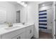Bright bathroom features double sinks, modern vanity, and a shower with blue stripped curtain at 14955 Lebeau Loop, Winter Garden, FL 34787